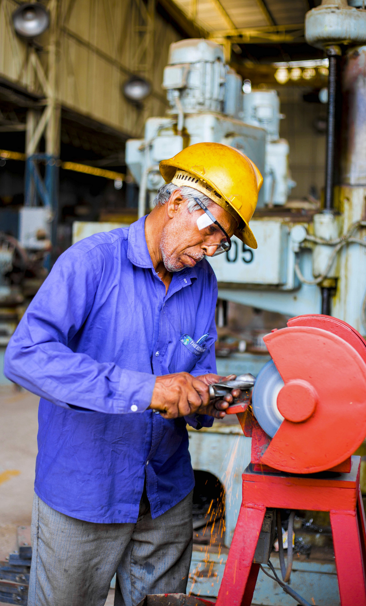 Industrial worker wearing a hard hat using a grinder